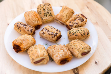 italian pastries with sesame seeds stuffed with sobrasada and cheese on a white plate on wooden table