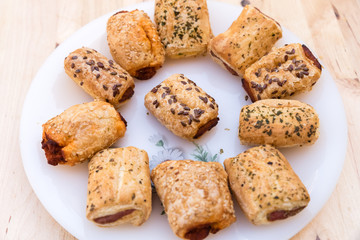 italian pastries with sesame seeds stuffed with sobrasada and cheese on a white plate on wooden table