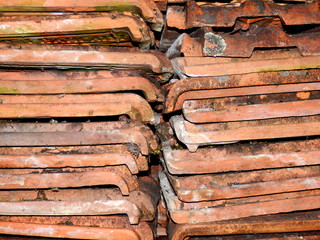 Old terracotta tiles removed from a workshop roof, covered in grime and lichen