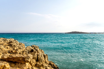 Beautiful summer Mediterranean landscape, lit by the afternoon sun. Pale blue sky and turquoise blue salty waters flooding the shore. Copy space.