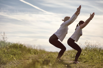 young sporty fit women doing yoga asana Utkatasana or chair pose. Do yoga outdoors