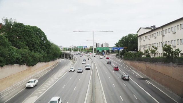 View from bridge over the highway E4 in Stockholm, Sweden. Cars, trucks and motorcycles in different lanes driving by in both directions.