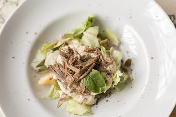 Warm salad with beef on a white plate.