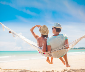 Young couple in love relaxing in a hammock by the beach