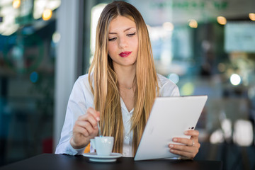 Fototapeta na wymiar Young businesswoman on a coffee break. Using tablet computer.