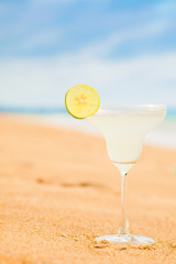 glass of fruit cocktail and sunglasses by the beach