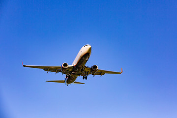 Passenger plane flying in the blue sky in sunlight rays