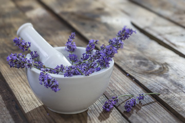 white ceramic mortar and pestle with fresh lavender on a old wooden background