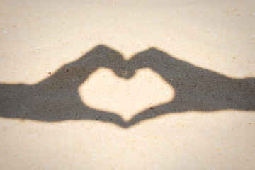 hand gesture heart shadow on the sand