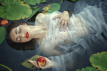 beautiful mermaid girl in a white dress in a swamp with water lilies