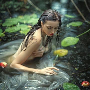 beautiful mermaid girl in a white dress in a swamp with water lilies