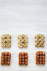 Vegan toasts with peanut butter, fruits and chia seeds on a white wooden table, from above. Healthy breakfast, dieting concept. Copy space.