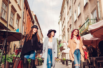 Outdoor shot of three young women walking on city street. Girls talking and having fun