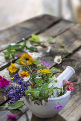wild flower and herb leaf in mortar on a old wooden table background with flower on the table