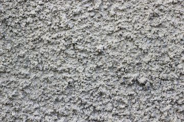 White color painted concrete wall with small stones. Granite stone stocco accidented background, ancient city building wallpaper