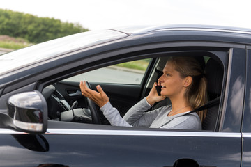 Junge Frau telefoniert beim Autofahren