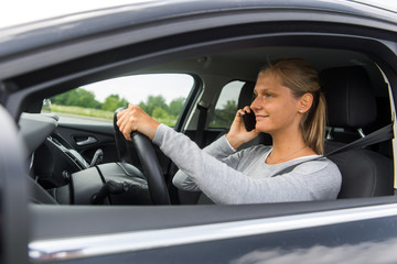 Junge Frau telefoniert beim Autofahren