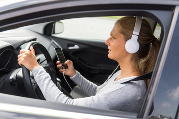 Junge Frau hört während der Fahrt Musik und schreibt eine SMS