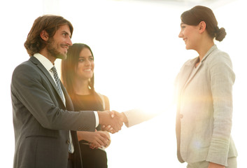 Businesspeople  shaking hands against room with large window loo