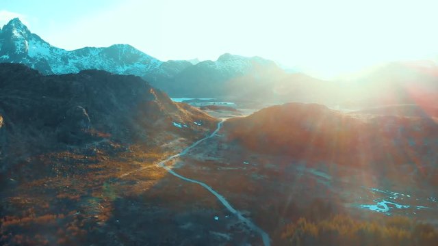 Drone flying in direction of the sun, over the moutains