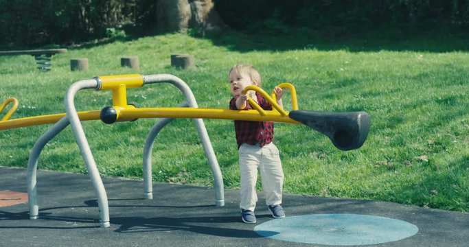 Little toddler boy playing on seesaw