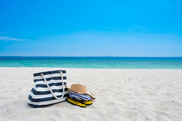 Straw hat, bag,towel and flip flops on tropical beach