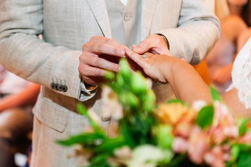 Groom putting wedding ring on bride's hand during ceremony