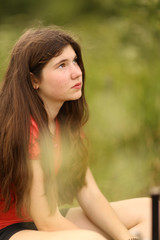 Fototapeta premium teenager girl with long thick brown hair outdoor portrait on green summer field background
