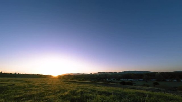 4K UHD mountain meadow timelapse at the summer or autumn time. Wild nature and rural field. Clouds, trees, green grass and sun rays movement.