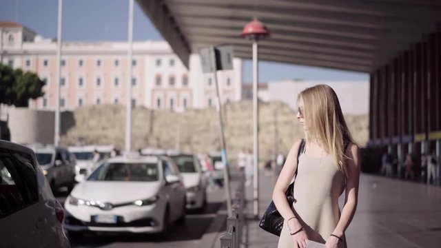 Young Attractive Blonde Girl tourist in the airport and stands at a taxi stop. Travelling Concept