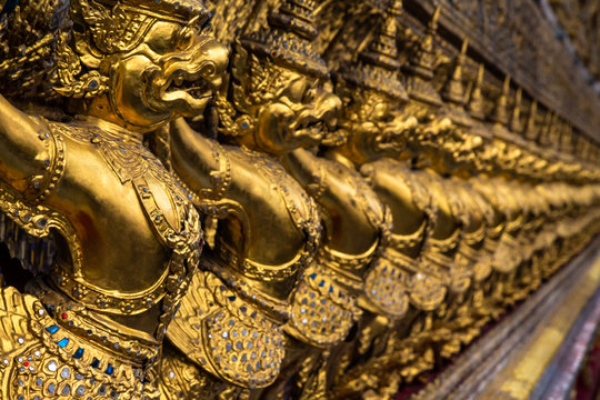 Row of golden Garuda figures from Thai mythology, adorning the interior of Wat Phra Kaew (Temple of the Emerald Buddha). Located in the Grand Palace, Bangkok, Thailand.