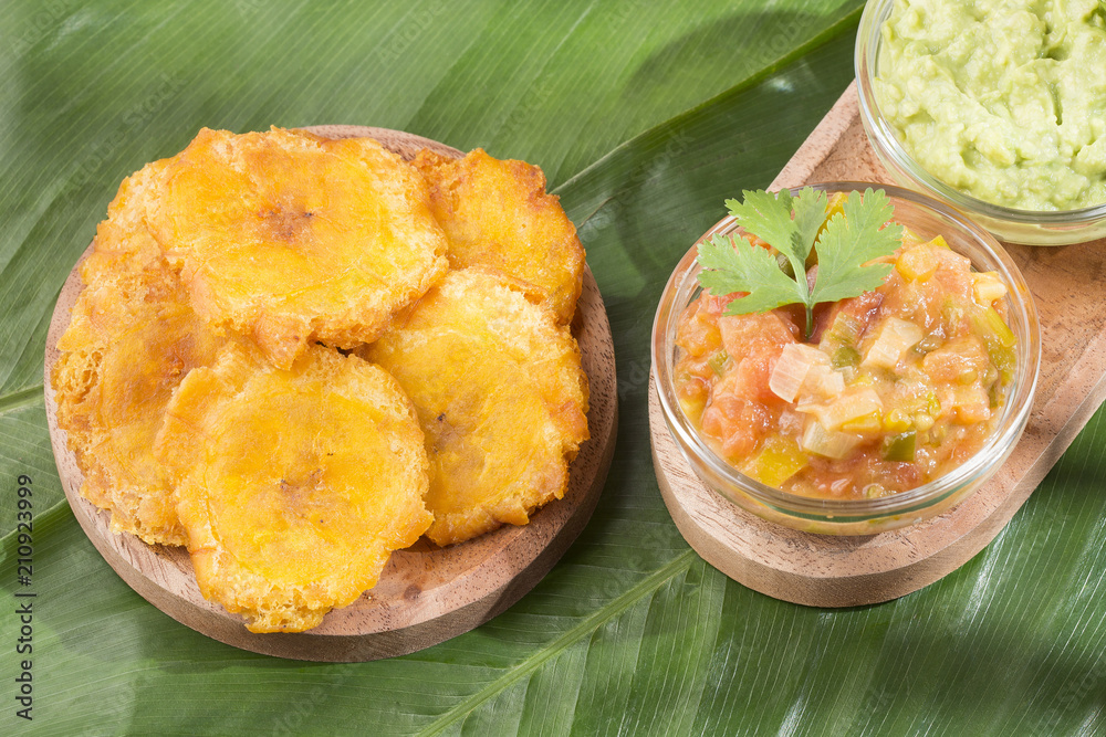 Canvas Prints Patacon or toston fried and flattened pieces of green plantain, traditional snack or accompaniment in the Caribbean, guacamole and tomato onion salad beside