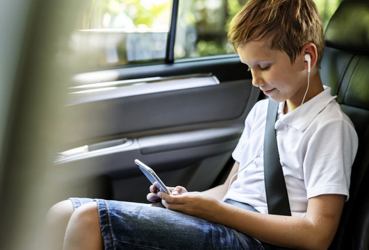 Boy playing on a smartphone in the car