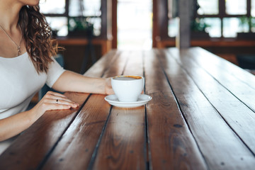 Female hands with a cup of coffee on a wooden table