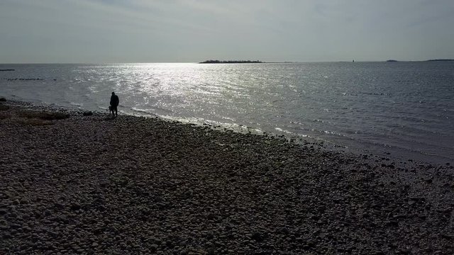 Man leisurely playing fetch with dog along the rocky coast
