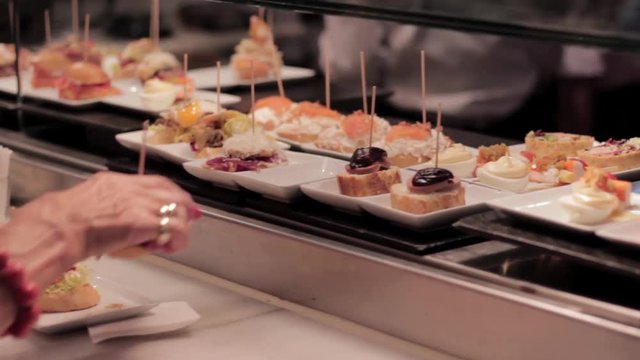 Old woman picking what to eat in a spanish tapas bar.