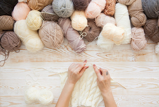 Wool and cotton yarn for knitting of neutral natural color. The woman knits knitting.