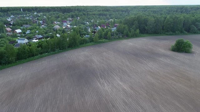 4k. Cinematic aerial footage. Beautiful small village near agricultural field in a beautiful green forest.