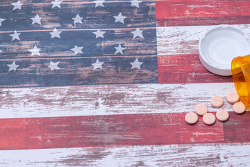 Bottle of pills spill on American flag with room for text