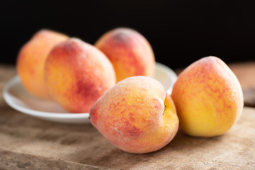 Ripe peaches on white dish and wooden, tropical fruit