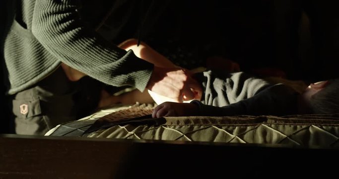 Father changes diaper on toddler -indoors on sunny day