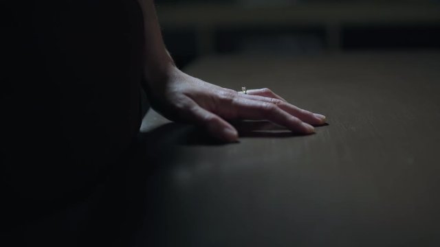 Woman rests her hand with engagement ring on a table