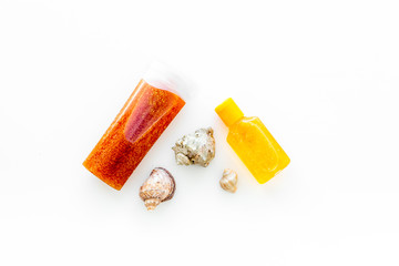 Sunscreen for sea vacation. Bottles with cream or lotion near sea shells on white background top view copy space