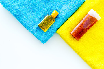 Sunscreen for sea vacation. Bottles with cream or lotion near towel on white background top view copy space
