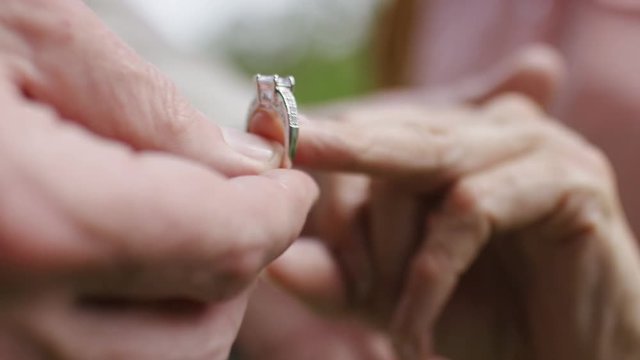 Hands of a senior couple as an engagement ring is put on, in slow motion