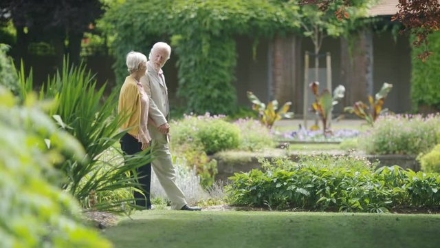 Senior romantic couple walking through beautiful gardens, in slow motion