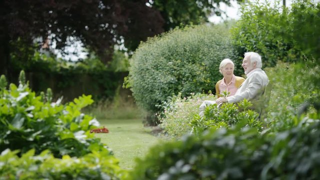 Senior retired couple enjoying time together on a bench in a beautiful garden
