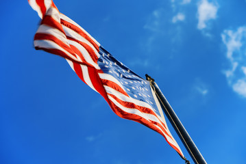 Star-striped American flag flutters proudly against the blue sky.