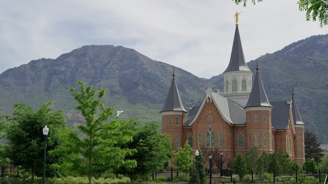 Static view of the Provo City Center Temple with Y Mountain in the background surrounded by green trees.