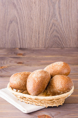 Fresh rye buns in a basket on a wooden table